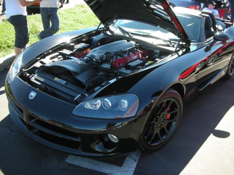1998 Ford Crown Victoria - black Dodge Viper sits with its hood up, exposing the red-lettered V10 engine, at an outdoor car show.