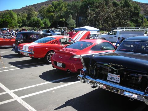 1998 Ford Crown Victoria - Rear view of a red Mustang fastback, a red Porsche 911 Turbo and a black 1957 Chevrolet parked in a car-show row.