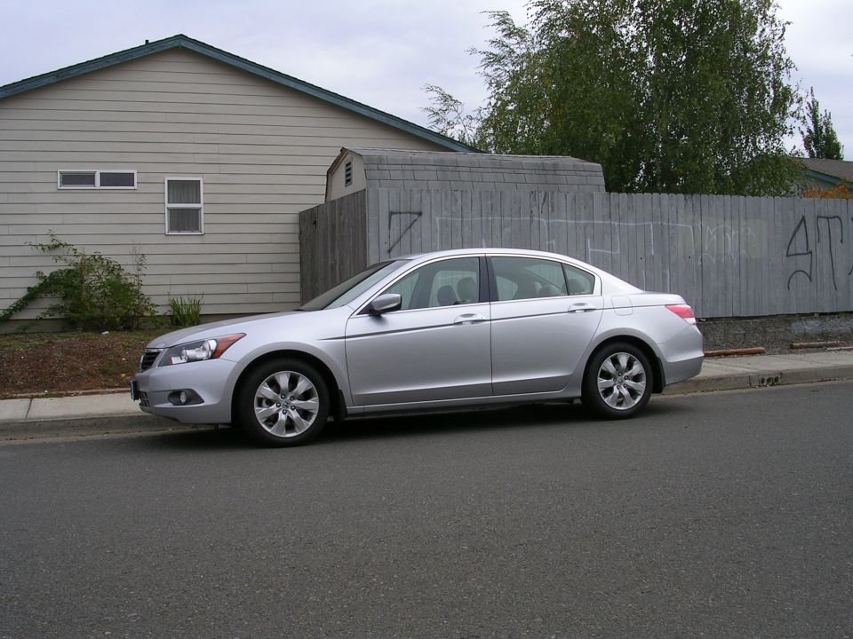Silver sedan parked curbside, side view