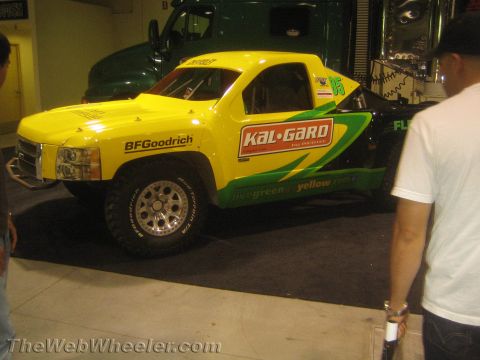1990 Ford Bronco - yellow and green off-road race truck with Kal-Gard and BFGoodrich livery and racing number 55 displayed at an indoor show.