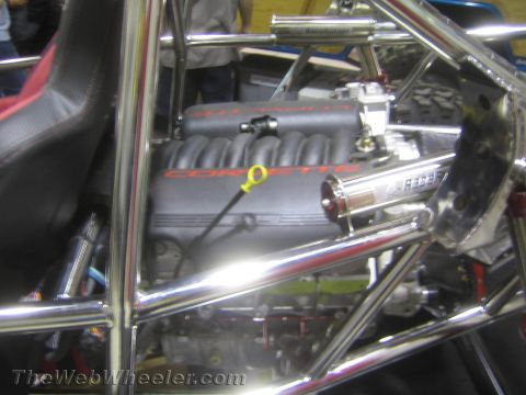 1990 Ford Bronco - Engine bay of a tube-frame buggy showing a black V8 engine with 'Corvette' lettering on the intake surrounded by polished chassis tubing.