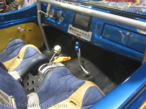 1990 Ford Bronco - Interior of a blue custom 4x4 showing tan-and-blue suede bucket seats, dual transfer-case shifters, a gauge cluster and a display screen.