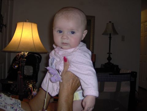 1978 Ford Bronco - A baby wearing a pink polka dot shirt is held up in front of lamps and a crib.