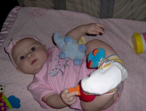 1978 Ford Bronco - A baby lies on a pink blanket surrounded by toys, including a blue stuffed animal and a colorful rattle.