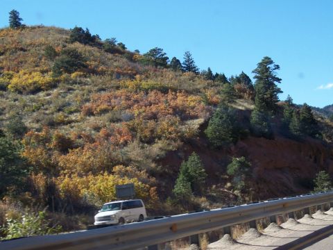 1972 Ford Ranchero - A white van travels along a highway bordered by a colorful hillside under a clear blue sky.