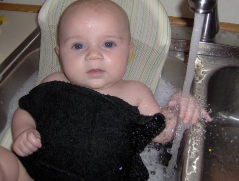 1978 Ford Bronco - A baby is being bathed in a sink with water running from the faucet.