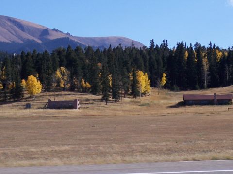 1972 Ford Ranchero - A wide view of a rural landscape autumn foliage and two rustic structures under a clear blue sky.