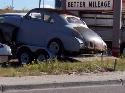 1972 Ford Ranchero - An old, rusty coupe sits on a trailer, with a 'For Sale' sign written on its rear window.