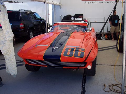 1971 Ford Mustang - This orange and blue race car, marked with the number 86, is parked inside a garage or tent.