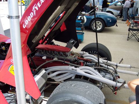 1971 Ford Mustang - Close-up view of a red race car's engine bay, revealing complex plumbing and a V12 engine.