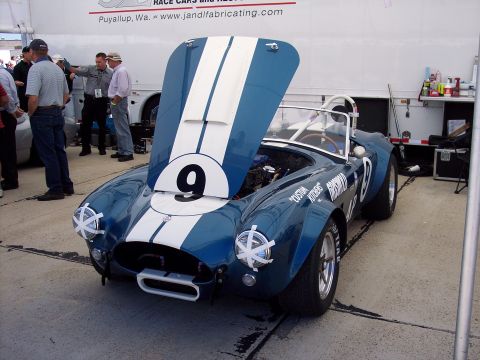 1971 Ford Mustang - A blue and white race car with its hood open, displaying the number 9 on the hood and racing decals on the fender.