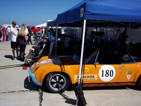 1971 Ford Mustang - A race car with various sponsor decals is parked under a blue canopy at an outdoor event.