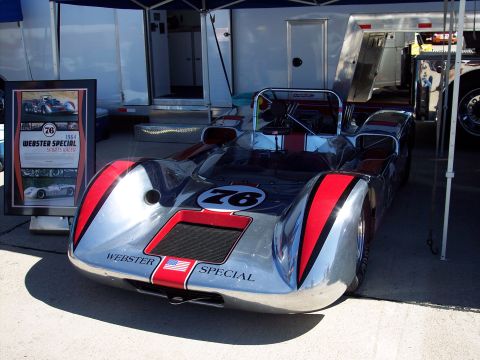 1971 Ford Mustang - A silver race car with red accents and the number 76 is displayed, with a framed document detailing its history.