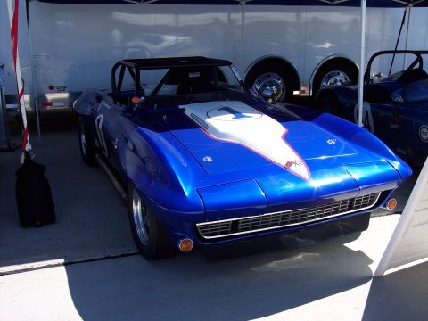 1971 Ford Mustang - A blue convertible race car with a white stripe and the number 1 on its hood is parked next to another vehicle.