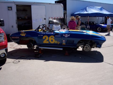 1971 Ford Mustang - A blue race car is up on jacks with its wheels removed, parked next to a trailer.