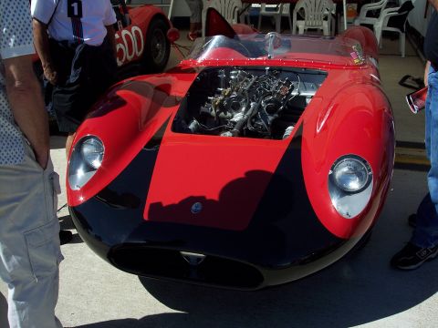 1971 Ford Mustang - A two-tone red and black race car is displayed with its engine compartment open, alongside another vintage race car.