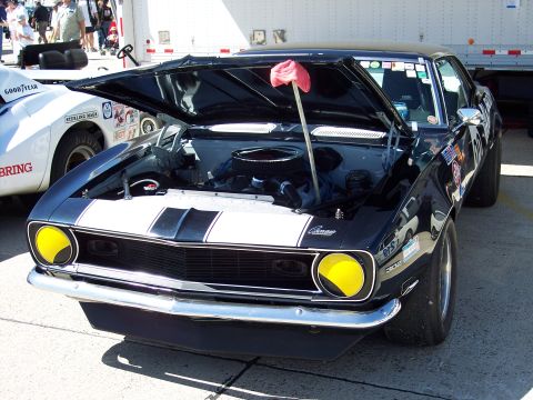 1971 Ford Mustang - Front view of a black 1969 Camaro SS with racing stripes and yellow fog lights, hood open.