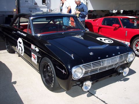 1971 Ford Mustang - A black 1963 Ford Falcon race car with racing decals and number 5 is parked next to a red Ford GT.