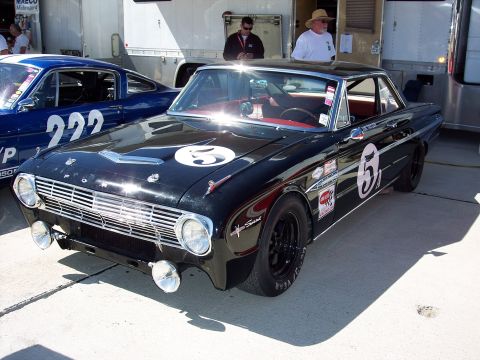 1971 Ford Mustang - A black 1963 Ford Falcon Sprint race car is parked next to another race car at an event.