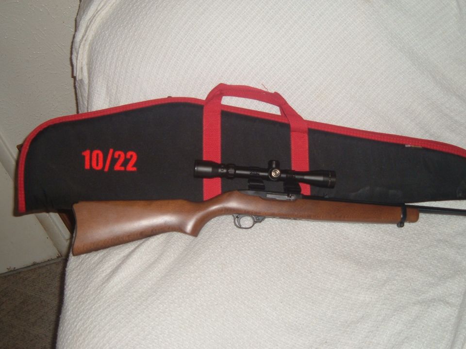 Wood-stocked rifle with scope on a black and red '10/22' gun case