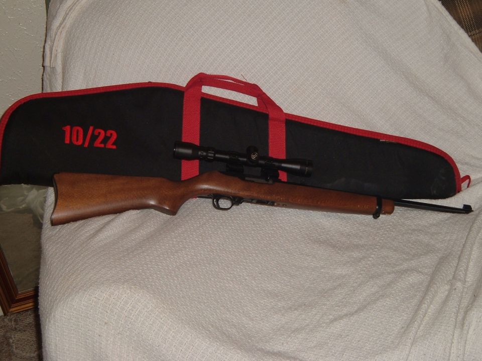 Wood-stock rifle with scope on a black and red '10/22' gun case