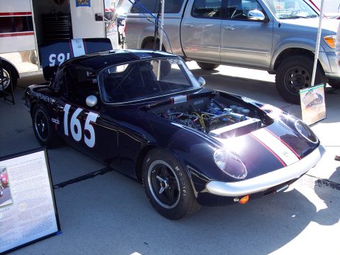 1971 Ford Mustang - A dark blue race car with white racing numbers and stripes is parked outdoors with its hood open.