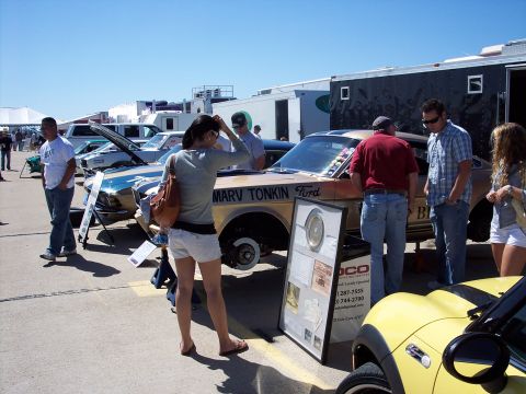 1971 Ford Mustang - A gold and blue 1971 Ford Mustang is displayed at an outdoor event, with people gathered around.