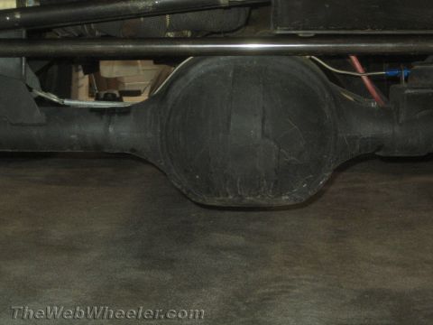 1990 Ford Bronco - close-up underbody view of a black rear axle differential housing and tubular components beneath a vehicle.