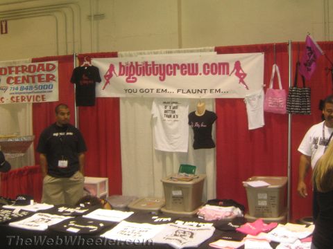 1990 Ford Bronco - merchandise booth displays T-shirts under a bigtittycrew.com banner with a vendor standing behind a table at a trade show.