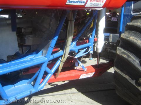 1990 Ford Bronco - underbody close-up shows a blue tubular chassis, transmission components and a red frame rail of an off-road vehicle.