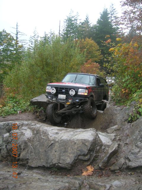 1996 Ford Bronco - A modified Ford Bronco navigates a challenging rocky trail on an overcast day.