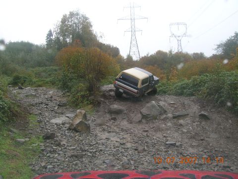 1996 Ford Bronco - A Ford Bronco navigates a challenging off-road course with power lines visible in the background.