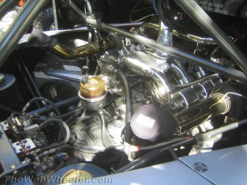1990 Ford Bronco - polished engine sits in a tube-chassis race vehicle, showing chrome headers, an oil filter, plumbing and a RYAN-branded cover.