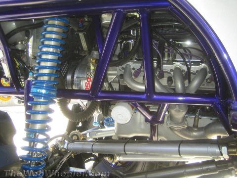 1990 Ford Bronco - detail view shows a blue coilover shock, driveshaft and engine plumbing inside a purple tube-chassis buggy.