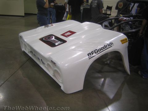 1990 Ford Bronco - white fiberglass off-road race car body bearing a BFGoodrich decal, shown from a high rear angle indoors.