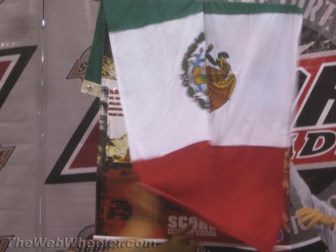 1990 Ford Bronco - Mexican flag with its green-white-red bands and central emblem hangs in front of racing banners at an event.