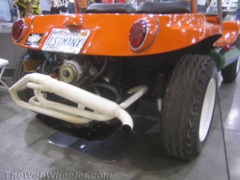 1990 Ford Bronco - tail of an orange dune buggy displays round taillights, a plate reading 1STMANX and a white tubular exhaust over an air-cooled engine.