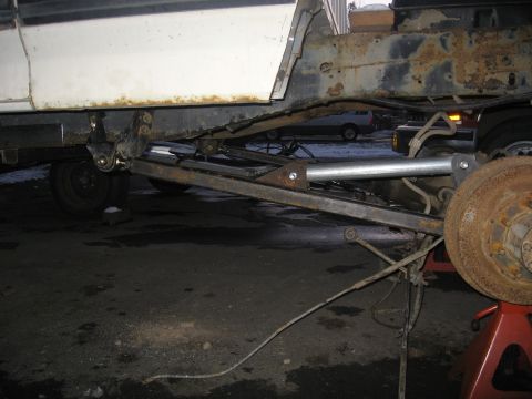 1990 Ford F-250 - The underside of a white truck is shown with significant rust and mechanical components, possibly undergoing repairs.