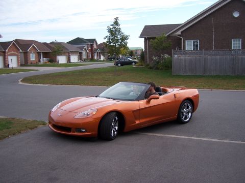 1996 Ford Bronco - Orange convertible cruises down a quiet suburban street.