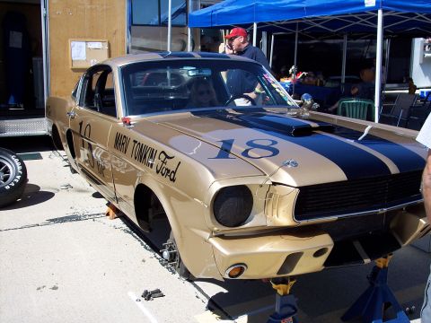 1971 Ford Mustang - A gold 1965 Ford Mustang race car with black stripes and the number 18 is raised on jack stands.
