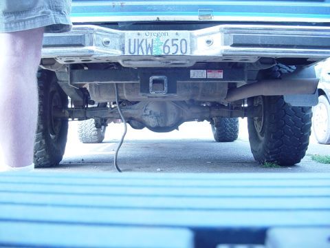 1985 Ford Bronco - The underside of a pickup truck, including the rear axle, suspension, and exhaust system, is shown from a low angle.