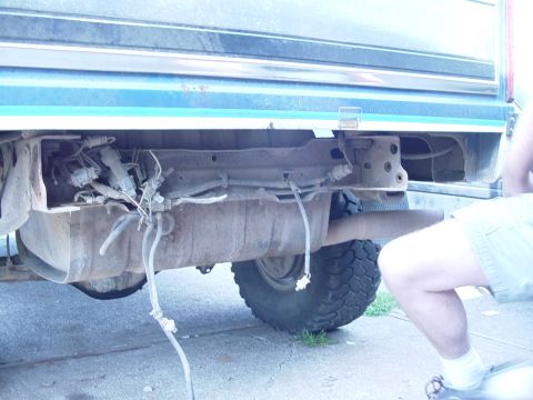 1985 Ford Bronco - The rear bumper area of a blue and green vehicle is shown, with exposed fuel lines and a spare tire visible.