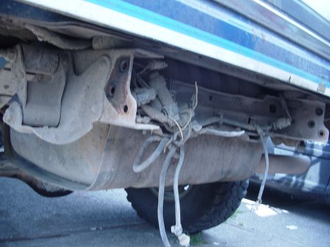 1985 Ford Bronco - Close-up of vehicle undercarriage, focusing on the fuel tank and exhaust system.
