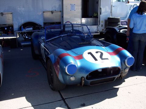 1971 Ford Mustang - A blue race car with red stripes and the number 12 is parked in front of an open trailer.