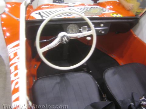 1990 Ford Bronco - interior of an orange dune buggy shows a white VW-logo steering wheel, a single gauge and black bucket seats.