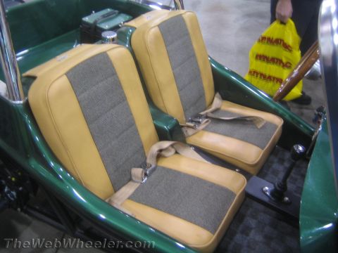 1990 Ford Bronco - Two tan-and-gray cloth bucket seats with lap belts sit inside the green fiberglass tub of a dune buggy; a yellow shopping bag is visible be…