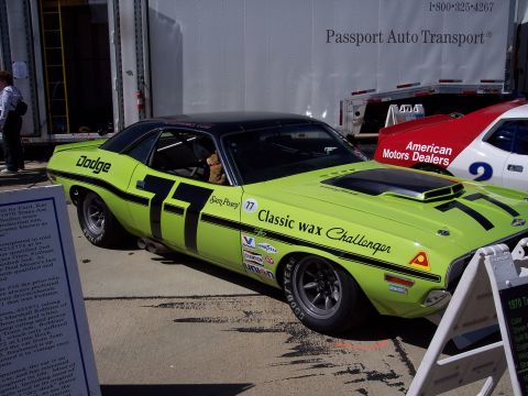 1971 Ford Mustang - Lime green 1970 Dodge Challenger race car with black stripes and number 77, parked next to another race car.