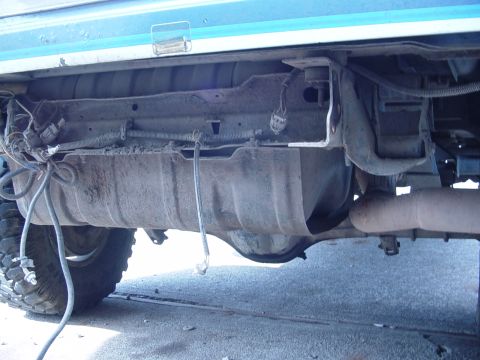 1985 Ford Bronco - The underside of a vehicle reveals its fuel tank and exhaust system.