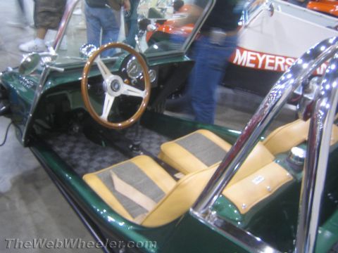 1990 Ford Bronco - Cockpit view of a green dune buggy showing a wood-rim steering wheel, chrome trim and tan checkered tuck-and-roll seats.