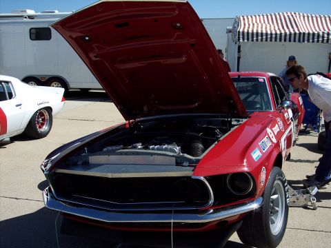 1971 Ford Mustang - A red 1969 Ford Mustang race car is parked with its hood up, revealing the engine bay.